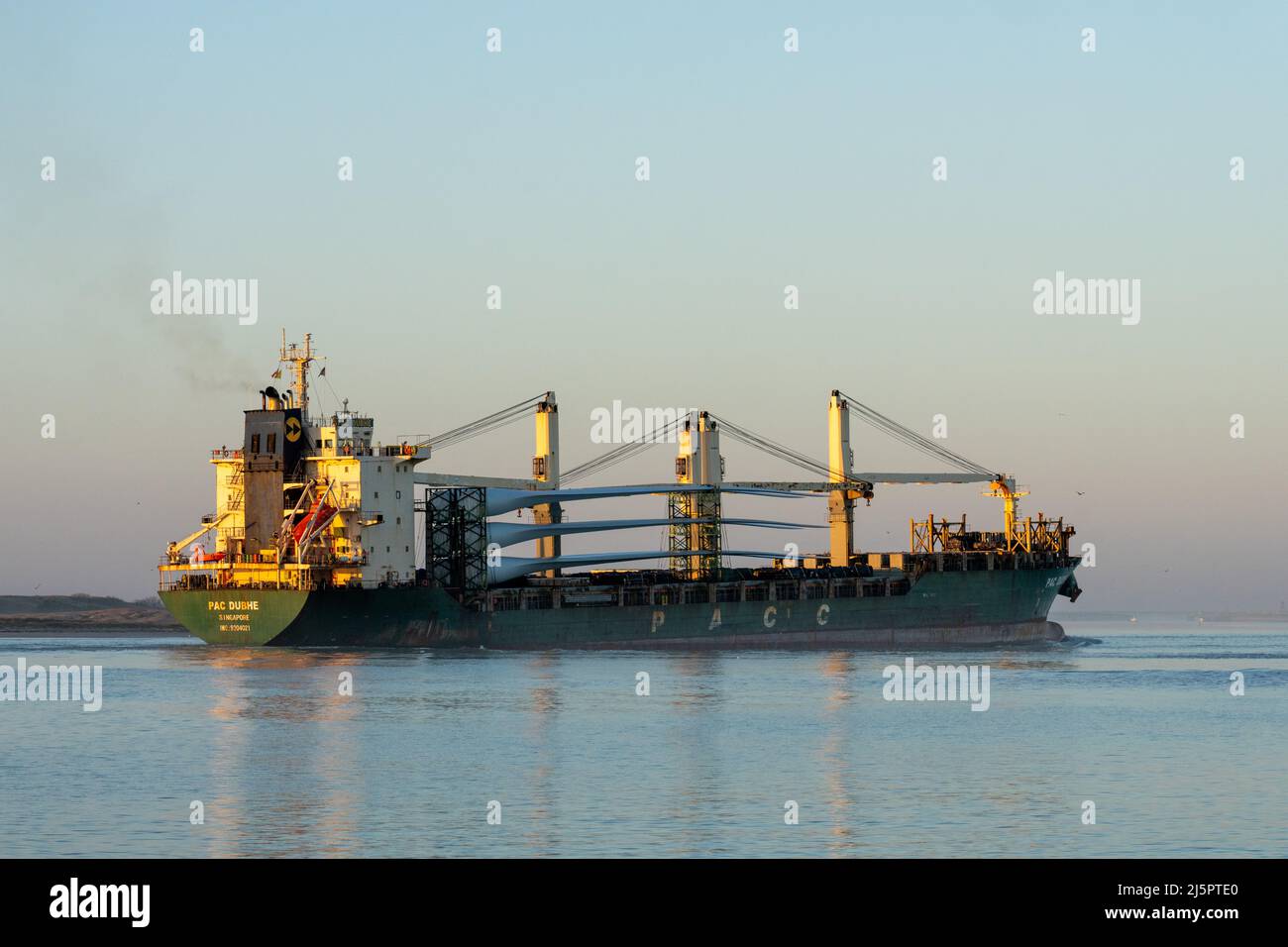 Ein großes Frachtschiff, das eine Ladung Windgeneratorflügel trägt, gelangt über South Padre Island, Texas, in den Brownsville Ship Channel. Stockfoto