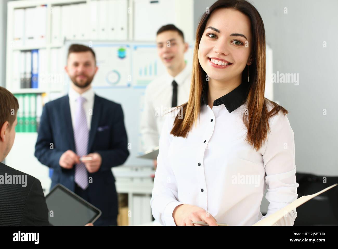 Lächelnder Manager posiert mit Kollegen im Büro, stylischer Look für die Arbeit Stockfoto