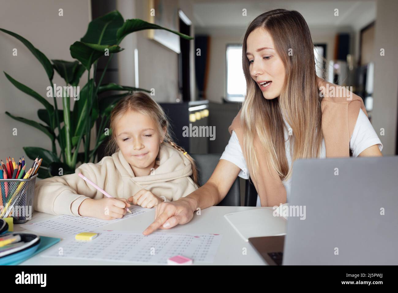 Kaukasische Familie arbeitet und studiert online zu Hause und mit einem Laptop. Fernunterricht oder Fernunterricht für Kinder. Ziemlich stilvolle Schulmädchen studieren Stockfoto