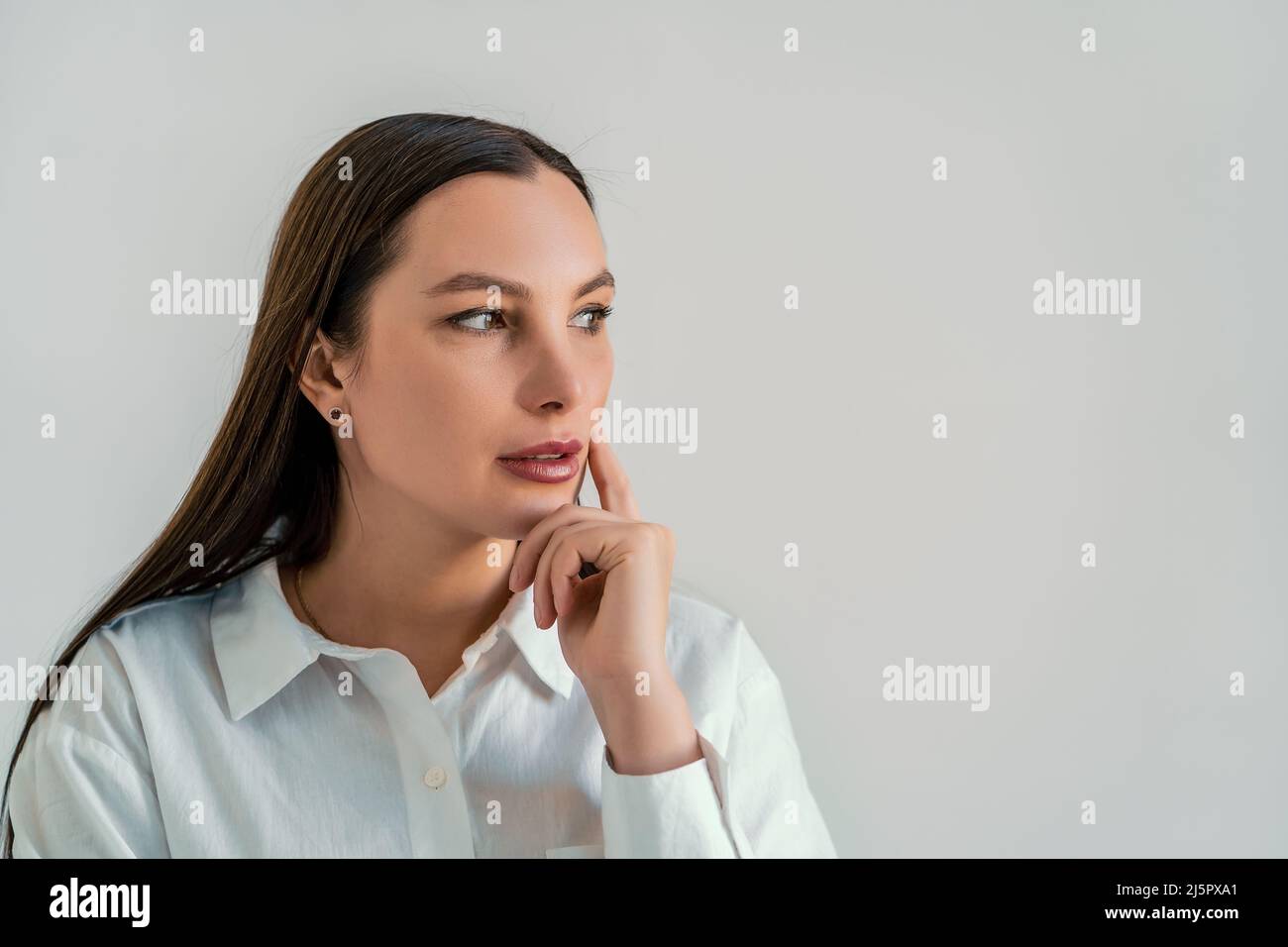 Nachdenkliche hübsche junge Frau, nachdenklicher Ausdruck, denkende Idee, während sie mit dem Kopierraum beiseite schaut. Stockfoto