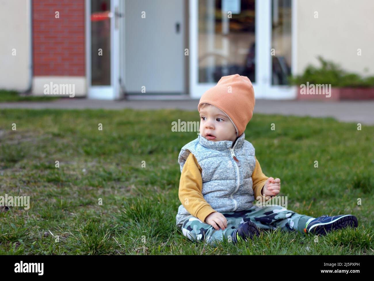 Ein Porträt eines einjährigen Jungen, der auf dem Rasen in Gdynia, Polen, sitzt Stockfoto