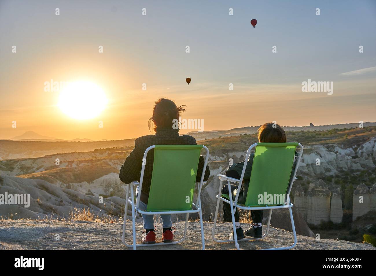 Mutter und Sohn entspannen sich und beobachten die Heißluftballons in Kappadokien, Türkei bei Sonnenaufgang Stockfoto