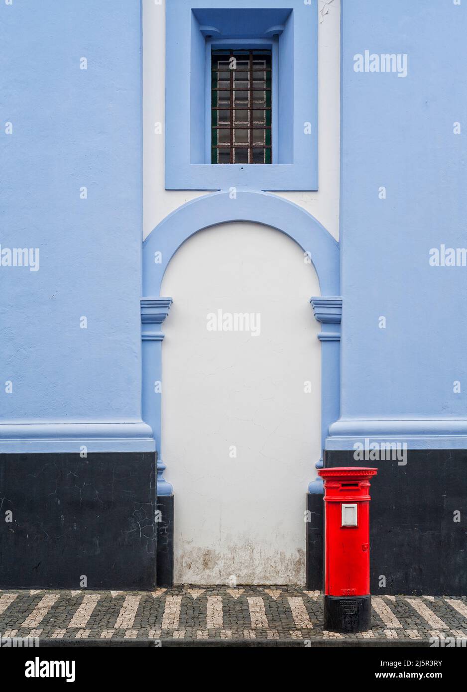 Roter Briefkasten vor dem blau-weißen Gebäude Stockfoto