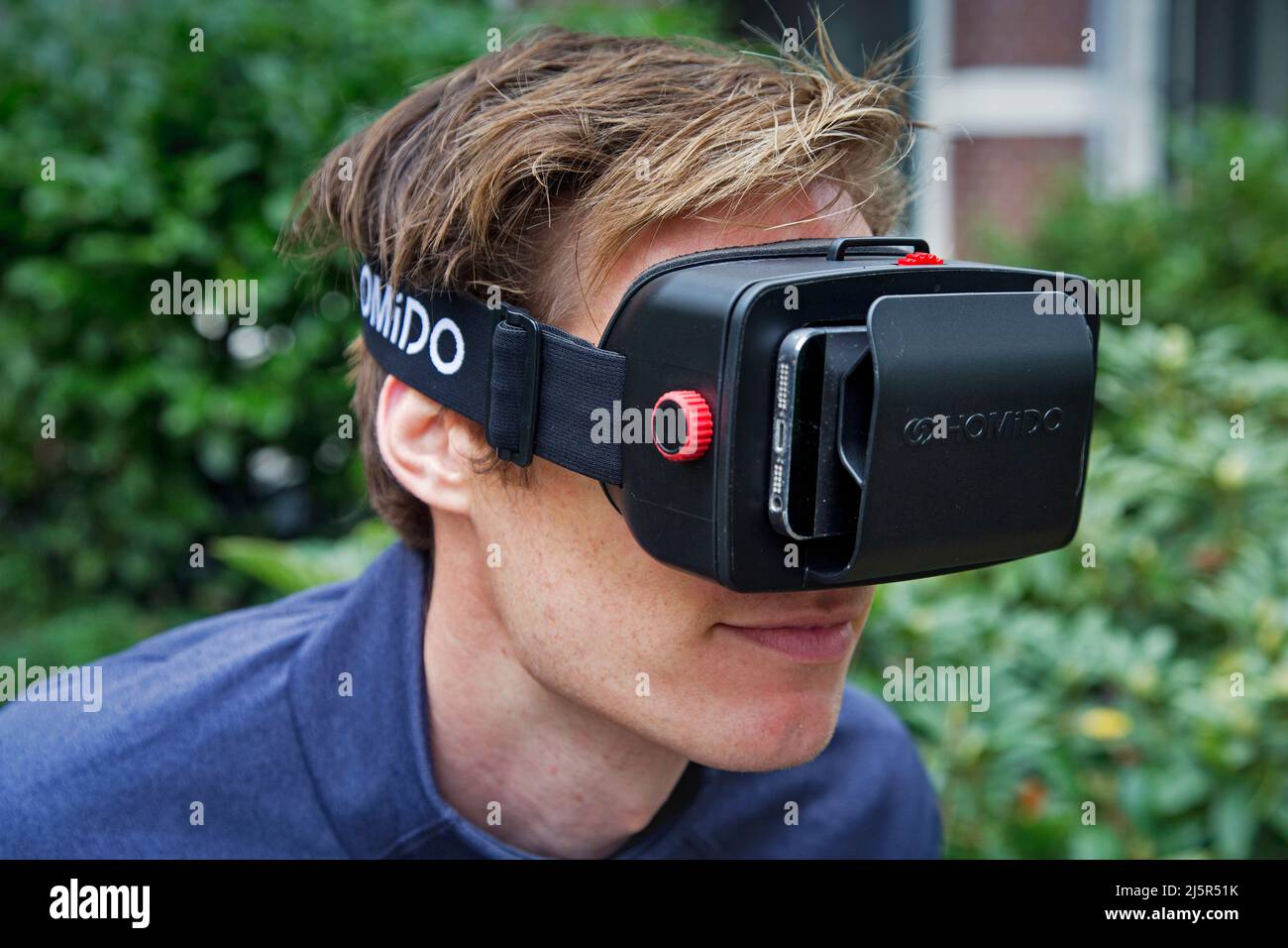 Der Benutzer eines VR-Sets sieht sich eine der Anwendungen auf seinem Smartphone-Bildschirm an. Das Virtual Reality-Headset ist ein Head-Mounted-Gerät, das vi bietet Stockfoto