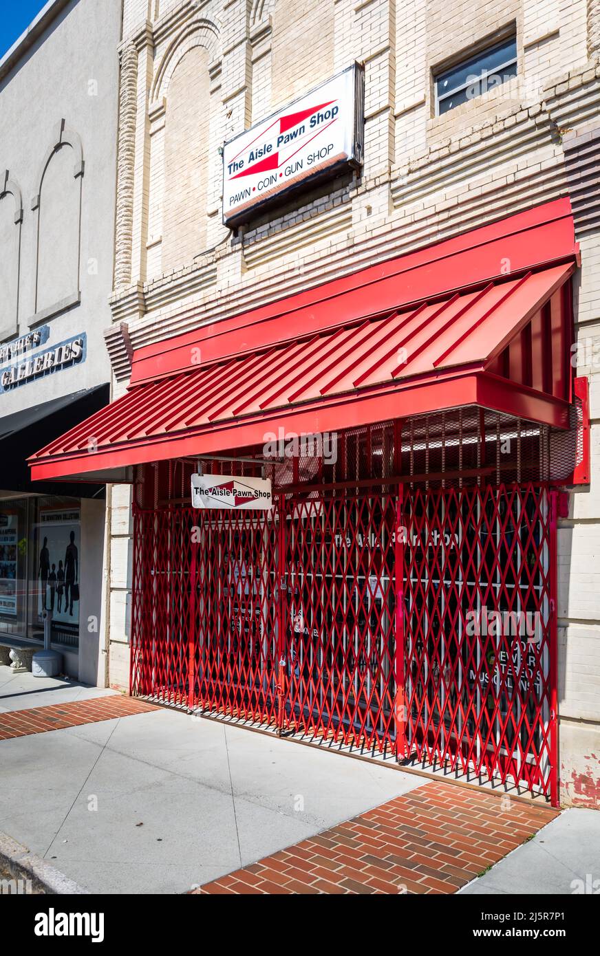 MOORESVILLE, NC, USA-17. APRIL 2022: Der Gangpawn Shop, geschlossen, mit Sicherheitstor gegenüber dem Eingang. Diagonale Perspektive. Stockfoto