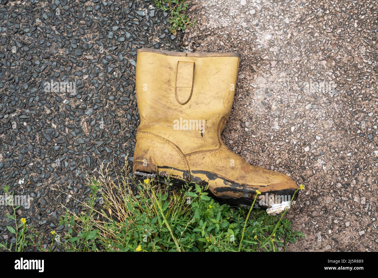 Gelber Rigger Stiefel wurde in der Hinterstraße der Stadt weggeworfen Stockfoto