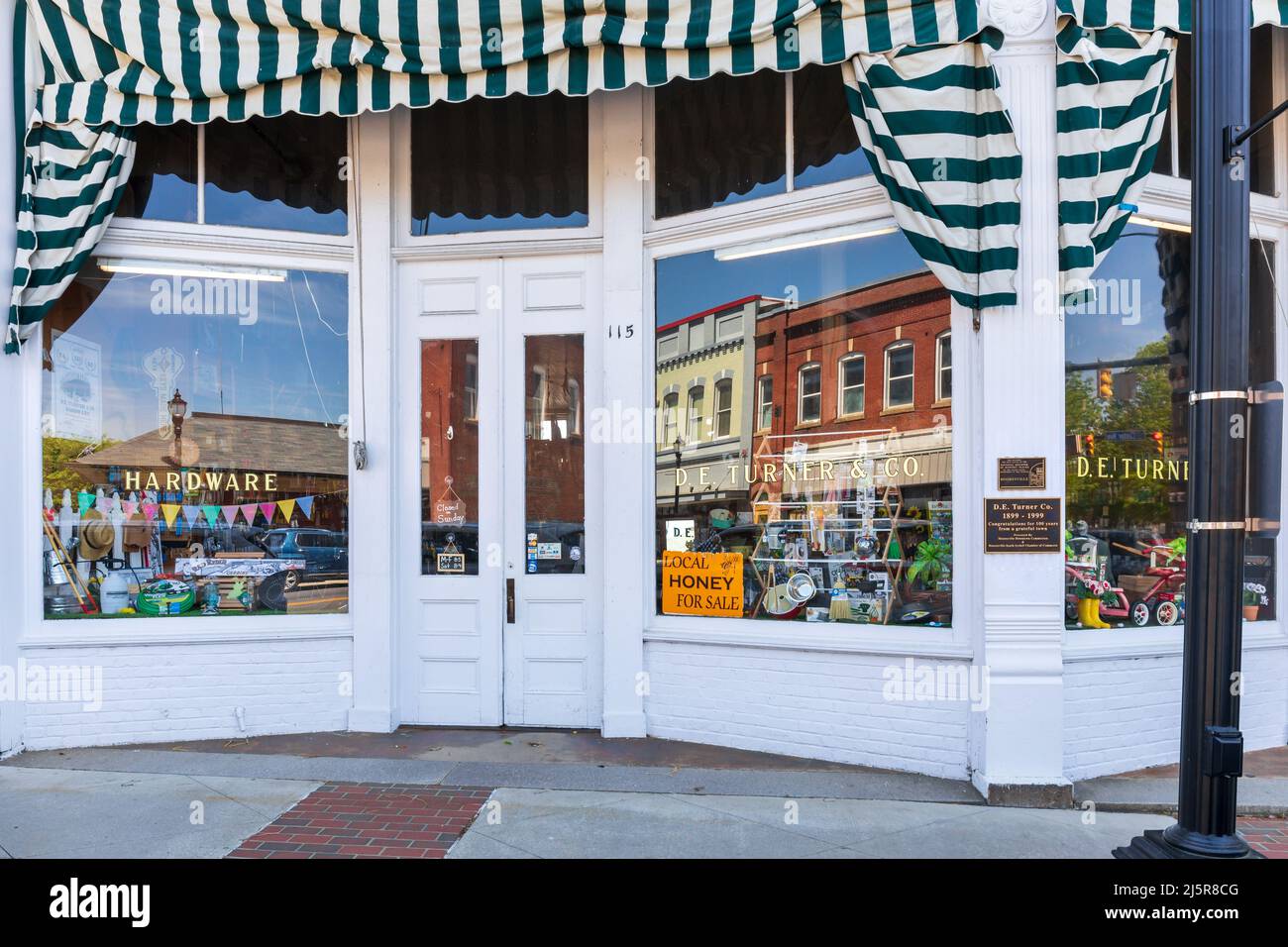 MOORESVILLE, NC, USA-17 APRIL 2022: Nahaufnahme des historischen D.F. Turner Eisenwarengeschäft, mit Eingang, Schaufenstern und Gedenktafel. Stockfoto