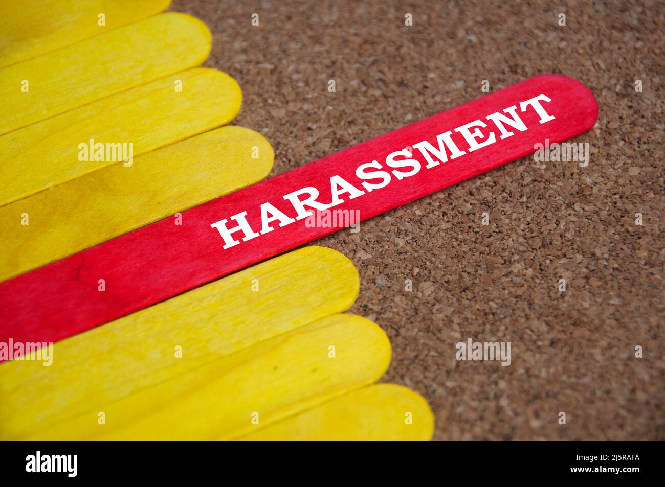 Belästigungstext auf rotem Holzstab, umgeben von gelben Stäben. Belästigungskonzept Stockfoto