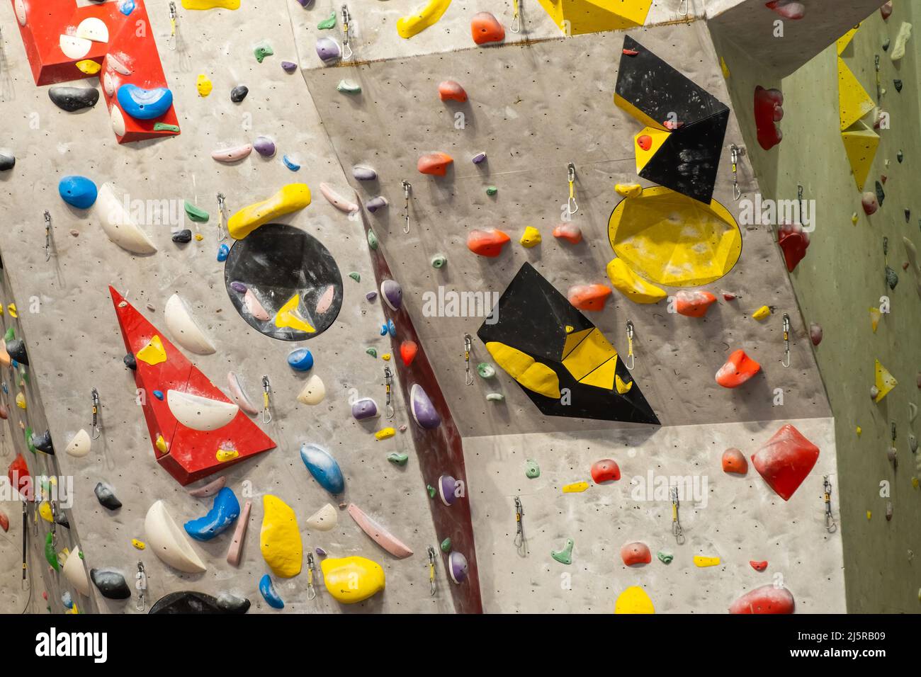 Künstliche Kletterwand mit verschiedenfarbigen Griffen. Stockfoto