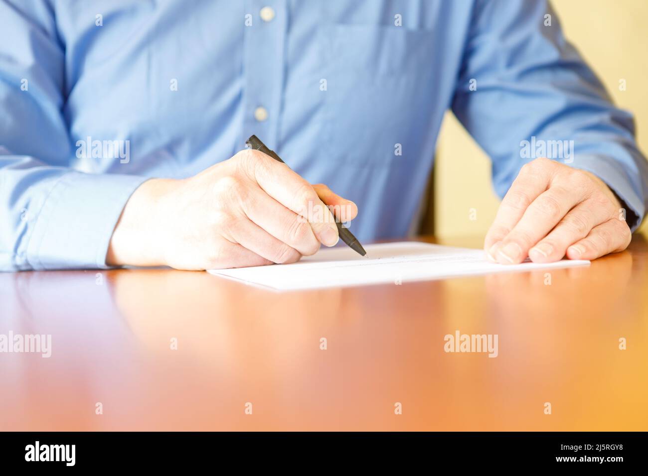 Ein Mann unterschreibt einen Vertrag auf dem Schreibtisch. Stockfoto
