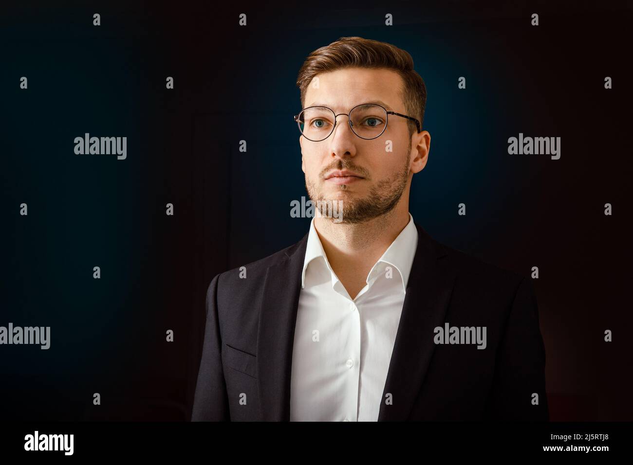 Porträt eines Geschäftsmannes in einem Anzug auf dunklem Hintergrund. Stockfoto