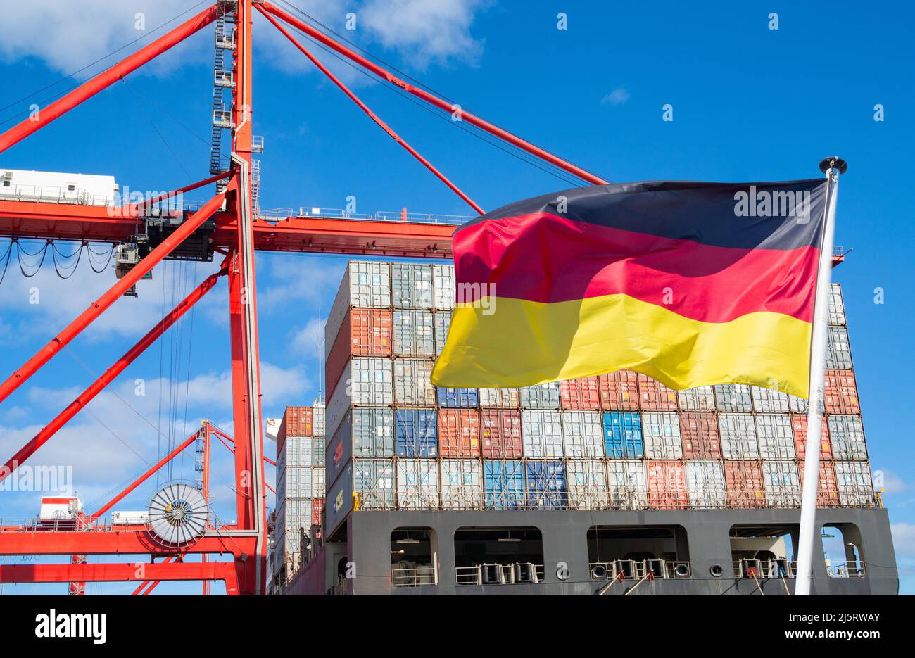 Containerschiff im Hafen mit Flagge Deutschlands. Deutsche Wirtschaft, Import, Export, Produktion, Arbeitsplätze, Rezession, Inflation... Konzept Stockfoto