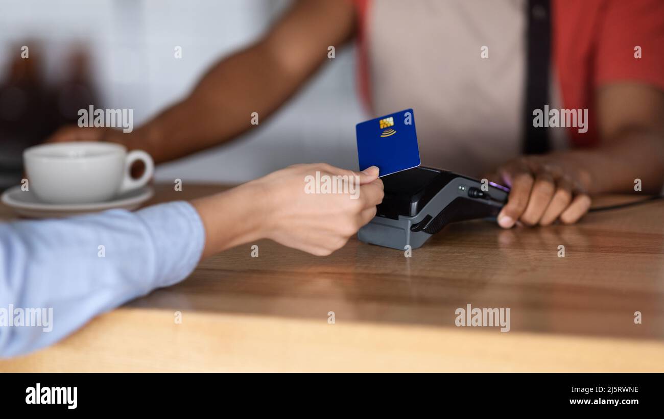 Der Kellner im Vorfeld des Millennial african american gibt dem Kunden Kaffee Stockfoto