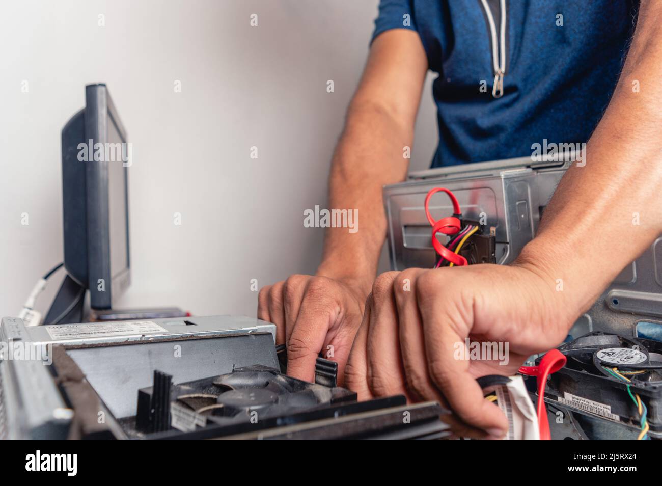 Junger Mann in einem Raum, der an der Computerwartung und -Reparatur arbeitet, unerkennbarer Computertechniker, der die Komponenten des Computerservice wechselt Stockfoto