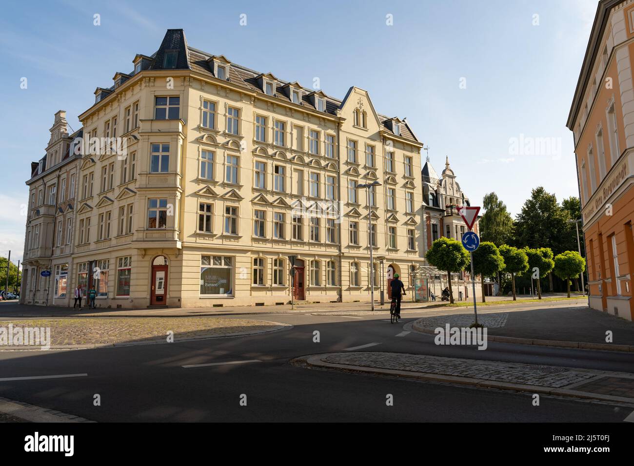 Gebäude in der Stadt bei einem schönen Sonnenuntergang. Ein Kreisverkehr ist vorne und ein Radfahrer fährt mit seinem Fahrrad. Das alte Haus. Stockfoto