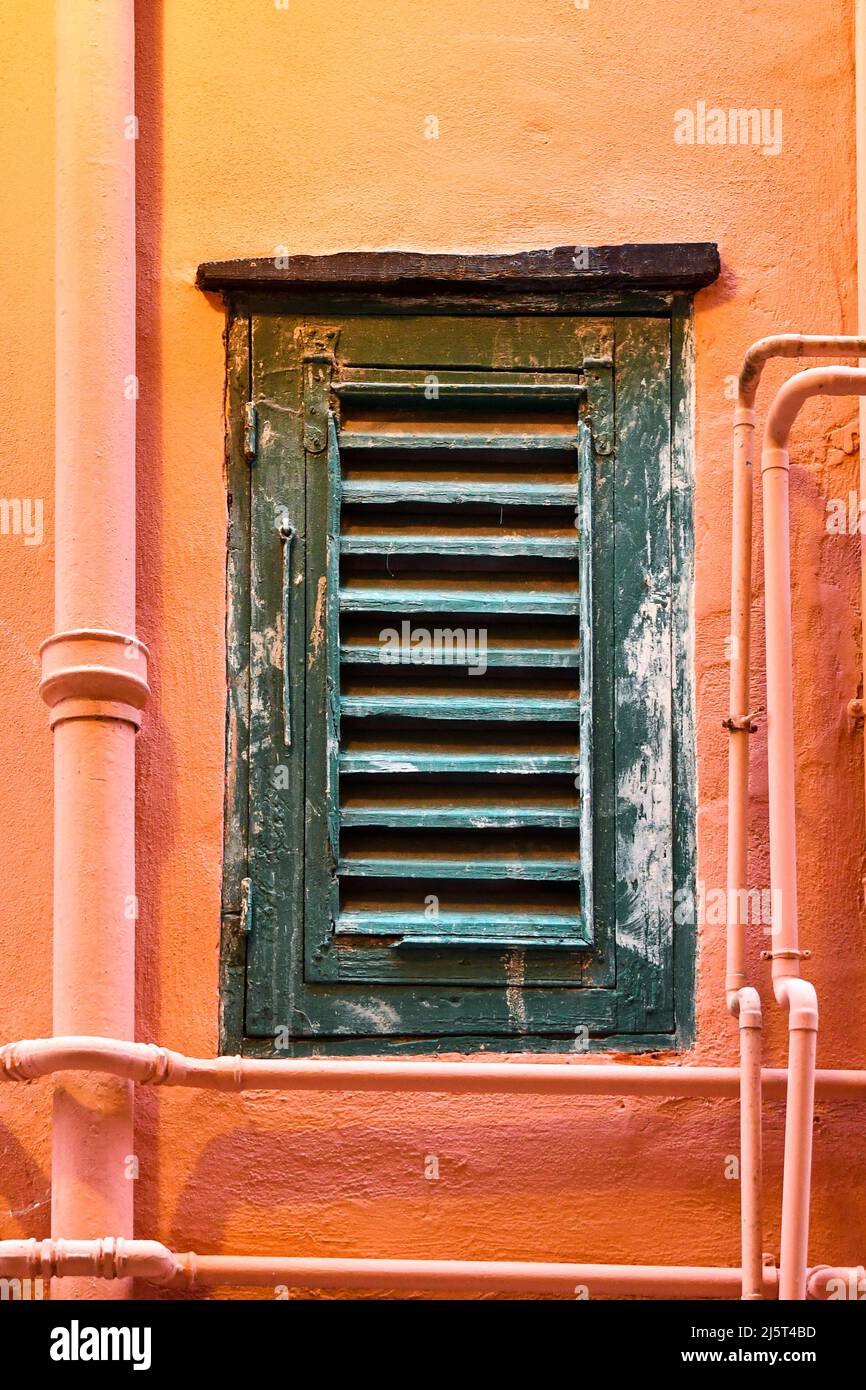 Detail des Fensters mit geschlossenen Holzfenstern eines alten Hauses mit rosa-oranger Wand, Sanremo, Imperia, Ligurien, Italien Stockfoto