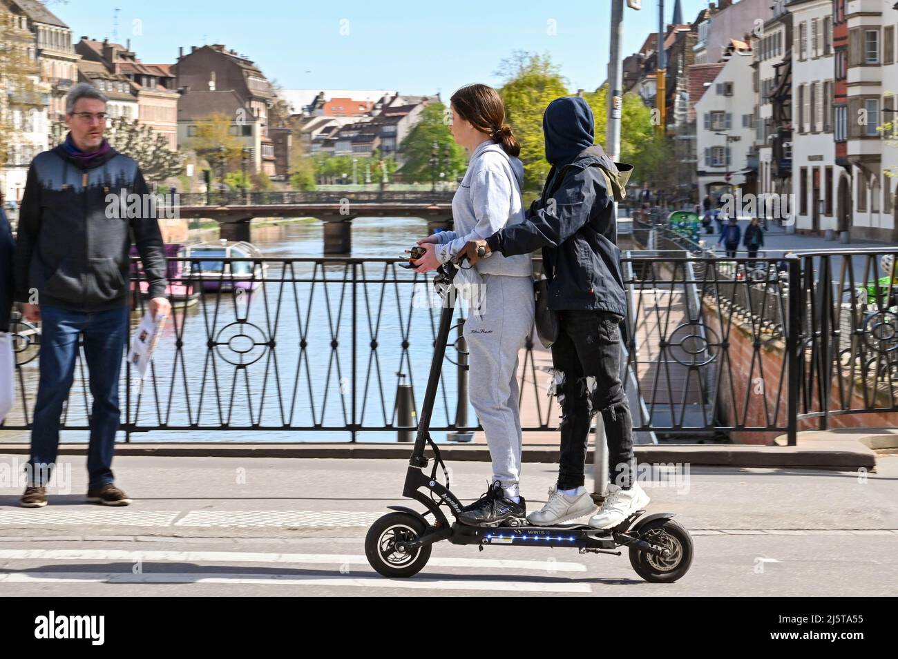 Straßburg, Frankreich - 2022. April: Zwei Personen fahren mit einem Elektroroller über eine Kanalbrücke in Straßburg. Stockfoto