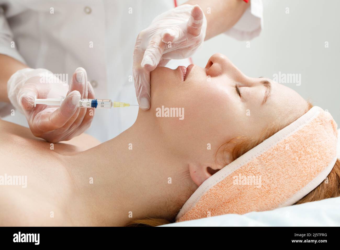 Der Kosmetologe führt das Kinnlift-Verfahren durch Injektionen von Schönheitsinjektionen durch. Arzt injiziert Hyaluronsäure in das ching einer Frau als Gesichtsbehandlung Stockfoto