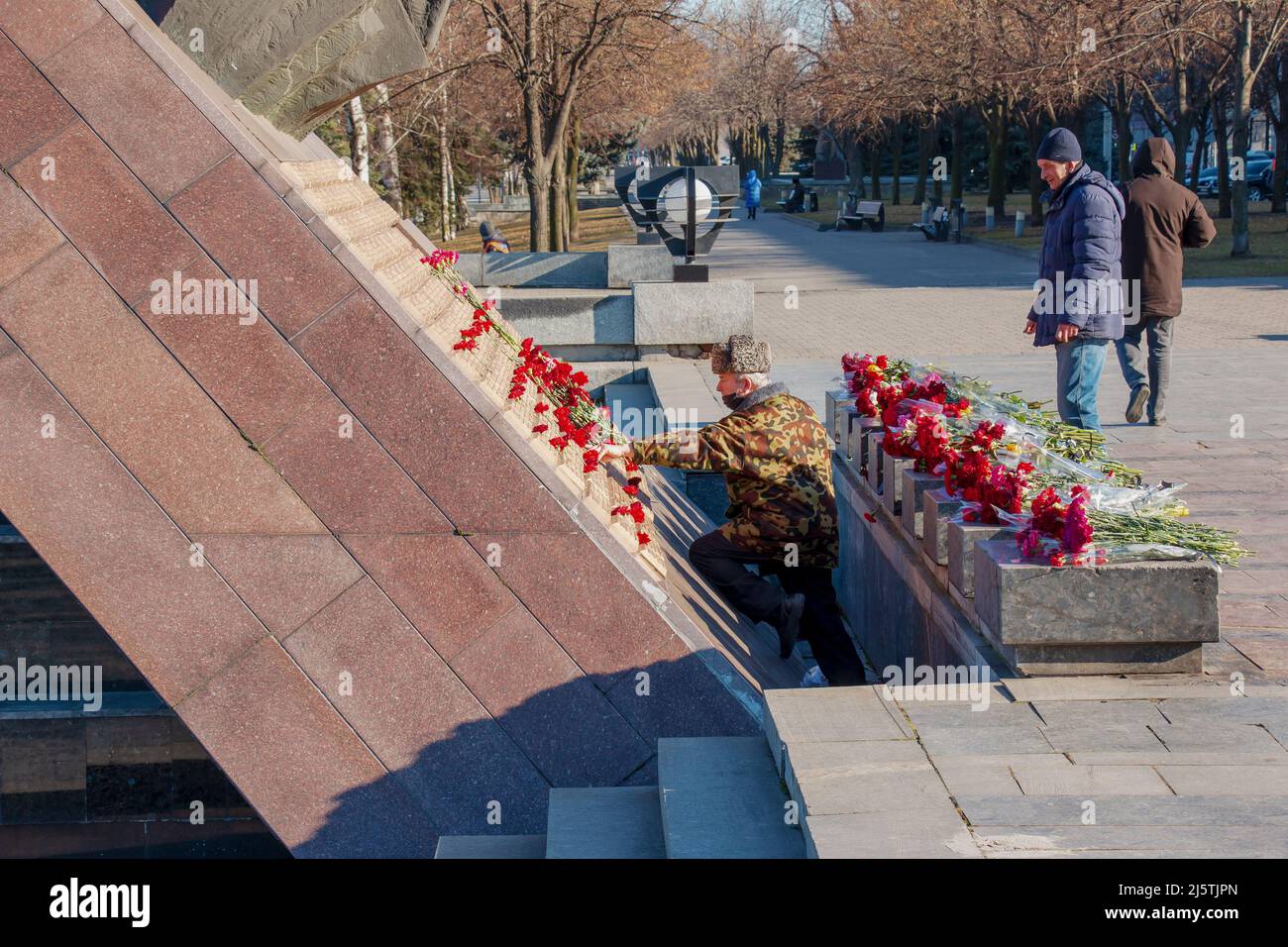 Dnipro, Ukraine - 15.02.2022: Denkmal für Veteranen des Afghanistankrieges 1979-1989. Rote Nelken auf der Granitplatte des Denkmals. Die Menschen ehren den m Stockfoto