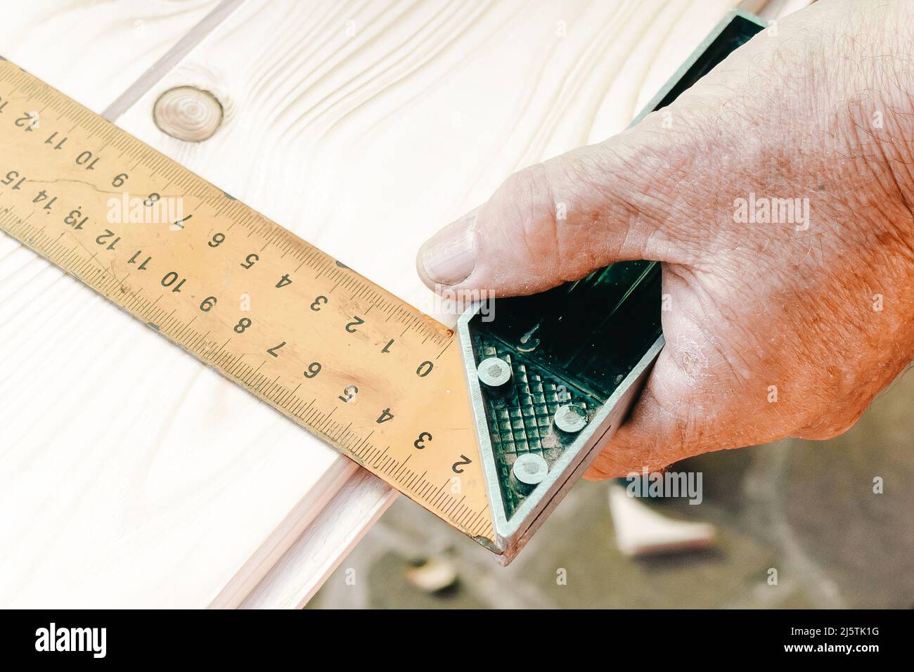 Nahaufnahme von Handwerkerhänden in messender Holzdiele mit Winkellineal und Bleistift. Holzbearbeitungskonzept. Stockfoto