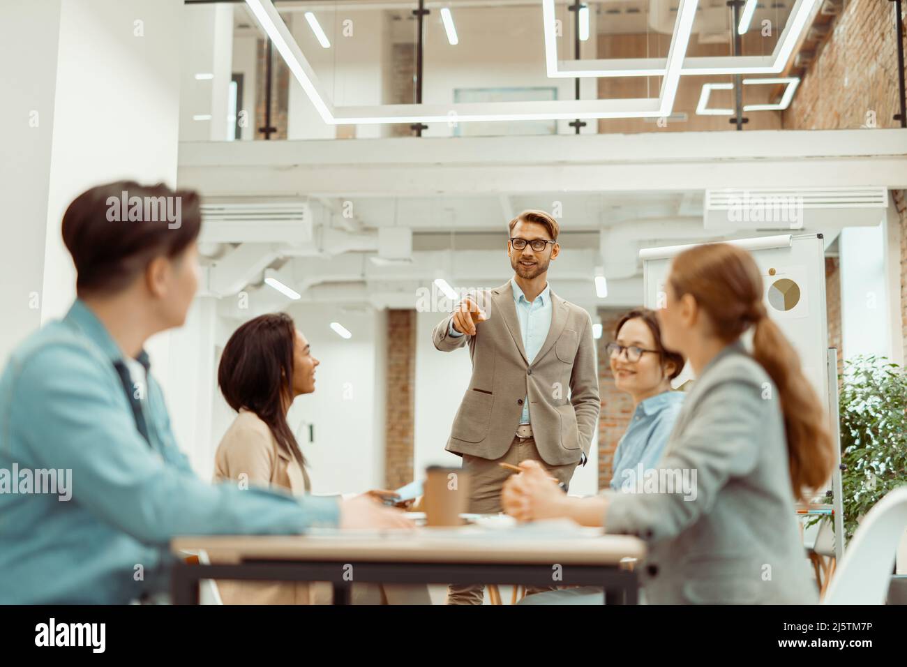 Der Vorgesetzter steht im Büro und erklärt den Kollegen neue Ideen Stockfoto