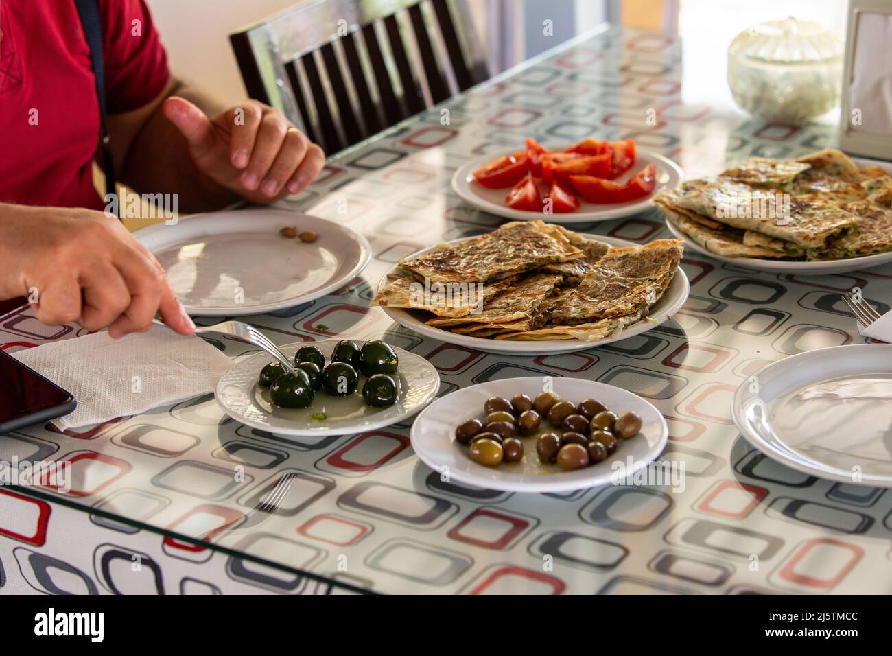 Der Mann, der am Frühstückstisch des Dorfes frühstückte. Verschiedene Frühstücksarten in der Türkei Stockfoto