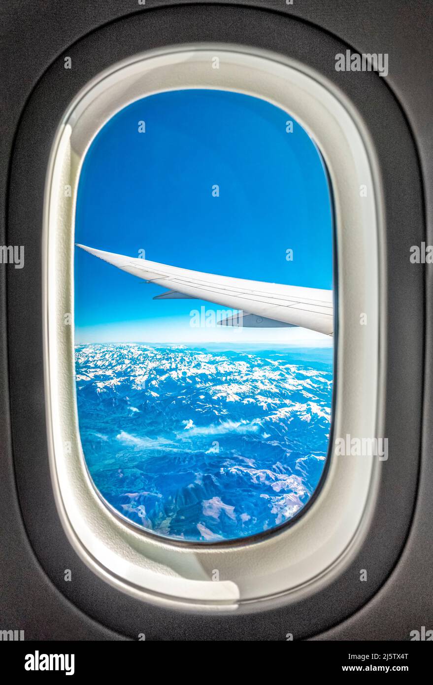 Blick aus dem Flugzeugfenster, das über schneebedeckte Pyrenäen fliegt. Blick aus einem Flugzeugfenster. Die Pyrenäen sind vom Flugzeugfenster aus schneebedeckt. Stockfoto