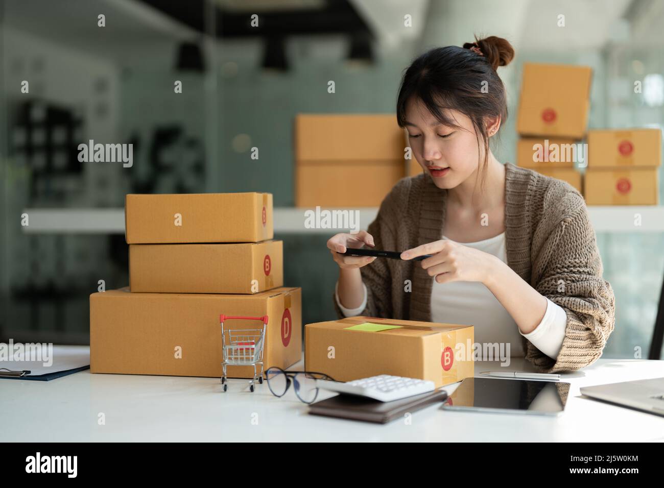 Junge asiatische Geschäftsfrau Besitzer Verpackung und nehmen Sie ein Foto auf Karton, Young Owner Woman Start Up for Business Online. Menschen mit Online-Shopping Stockfoto