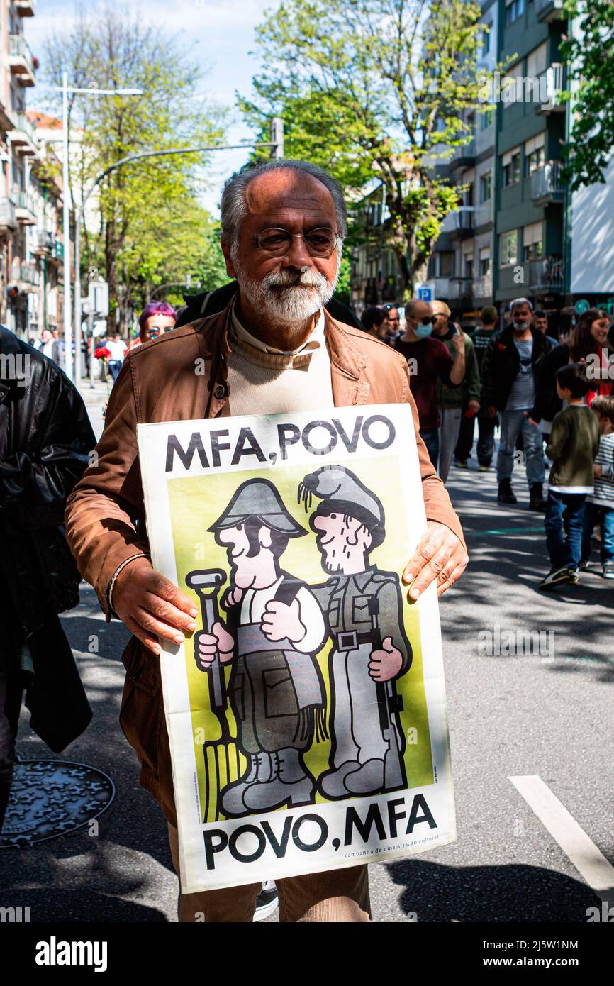 Porto, Portugal. 25. April 2022. Ein älterer Demonstrator hält eine Kopie des berühmten MFA-Posters des Designers João Abel Manta. Die Parade vom 25.. April feiert die Nelkenrevolution, die 1974 stattfand. In Porto organisierten zivile Bewegungen eine Parade, die vor der inzwischen ausgestorbenen PIDE (politische Polizei) begann und direkt im Herzen der Stadt in der Avenida dos Aliados (Allies Avenue) endete. Kredit: SOPA Images Limited/Alamy Live Nachrichten Stockfoto