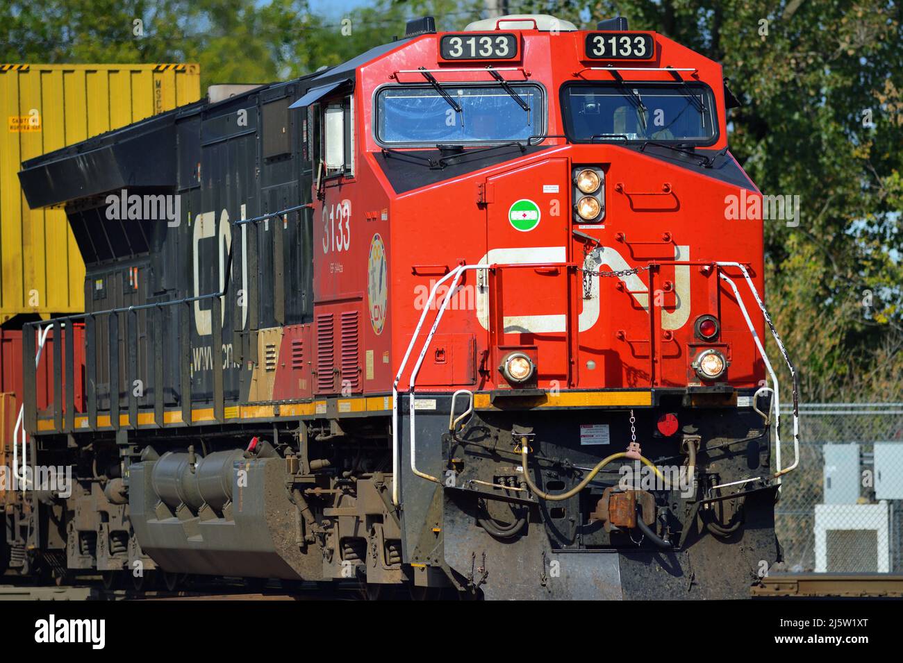 Elgin, Illinois, USA. Eine einzige Lokomotive der Canadian National Railway führt einen intermodalen Güterzug durch einen Diamantenübergang. Stockfoto