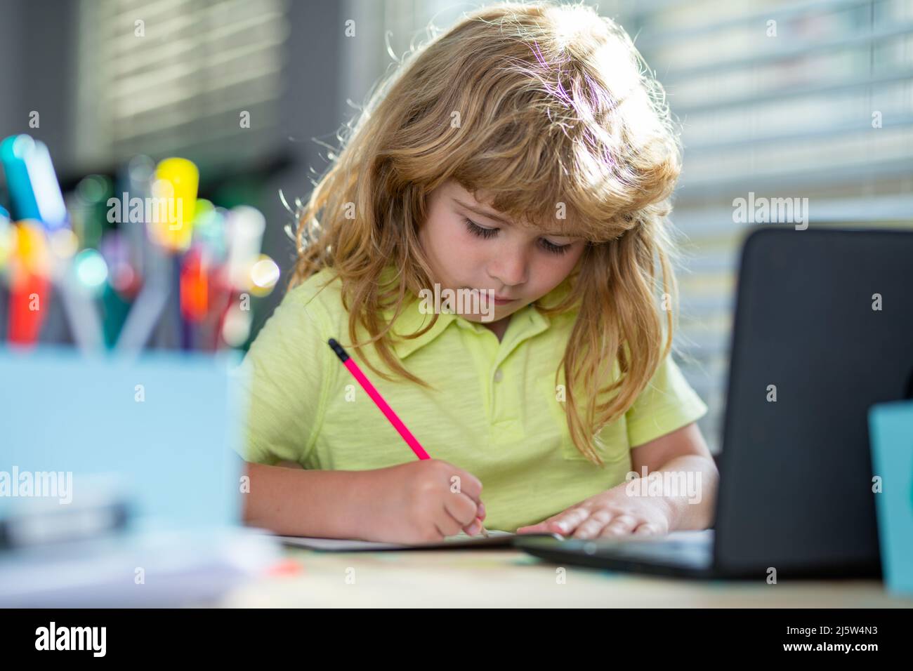 Kind schreibt in der Schule. Ein Junge im Schulalter macht zu Hause Hausaufgaben. Porträt eines kleinen Schuljungen, der am Tisch sitzt und Hausaufgaben macht. Intelligentes Child-tun Stockfoto