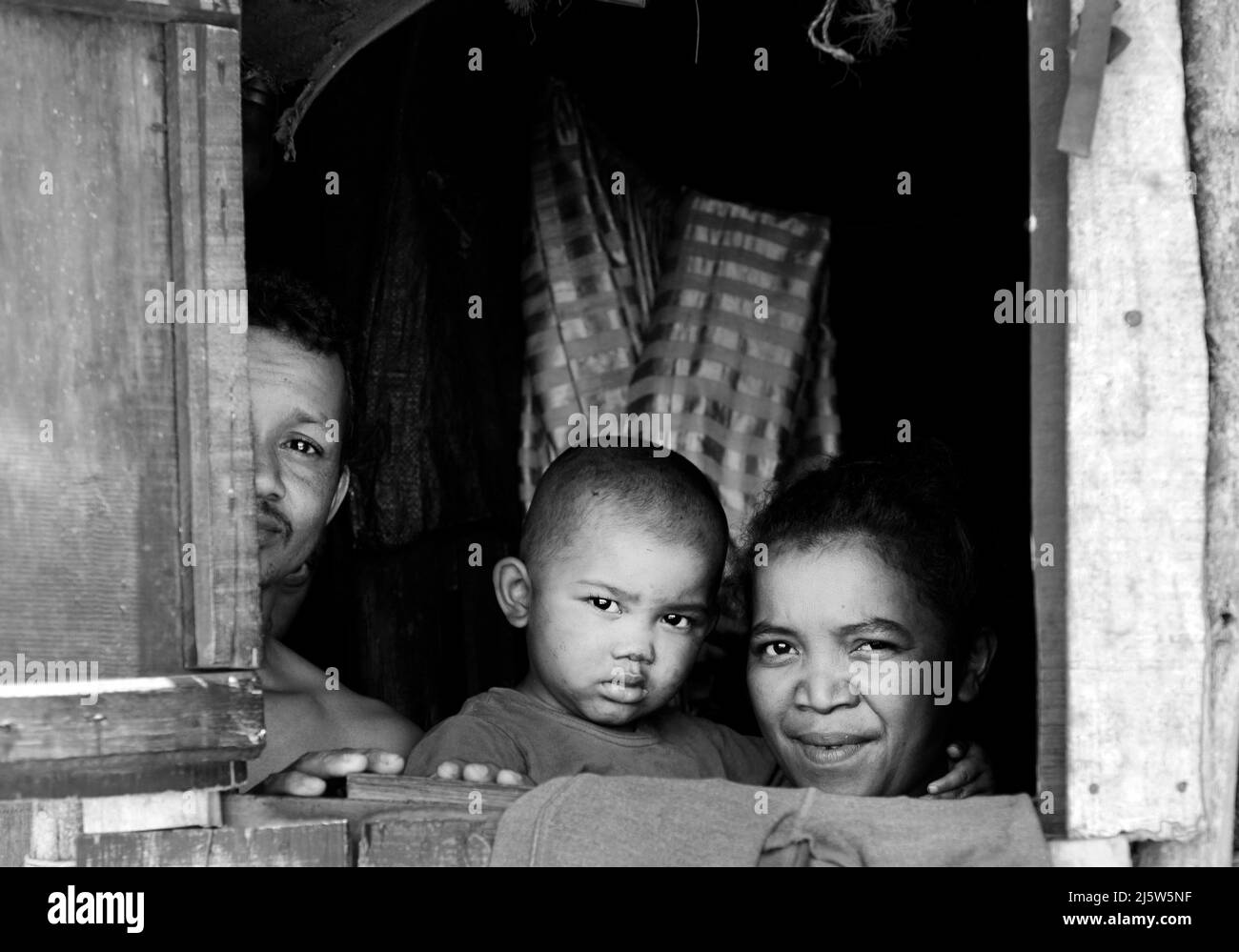 Eine madagassische Familie blickt aus ihrem Heimatfenster. Ambohimanga Region, Madagaskar. Stockfoto