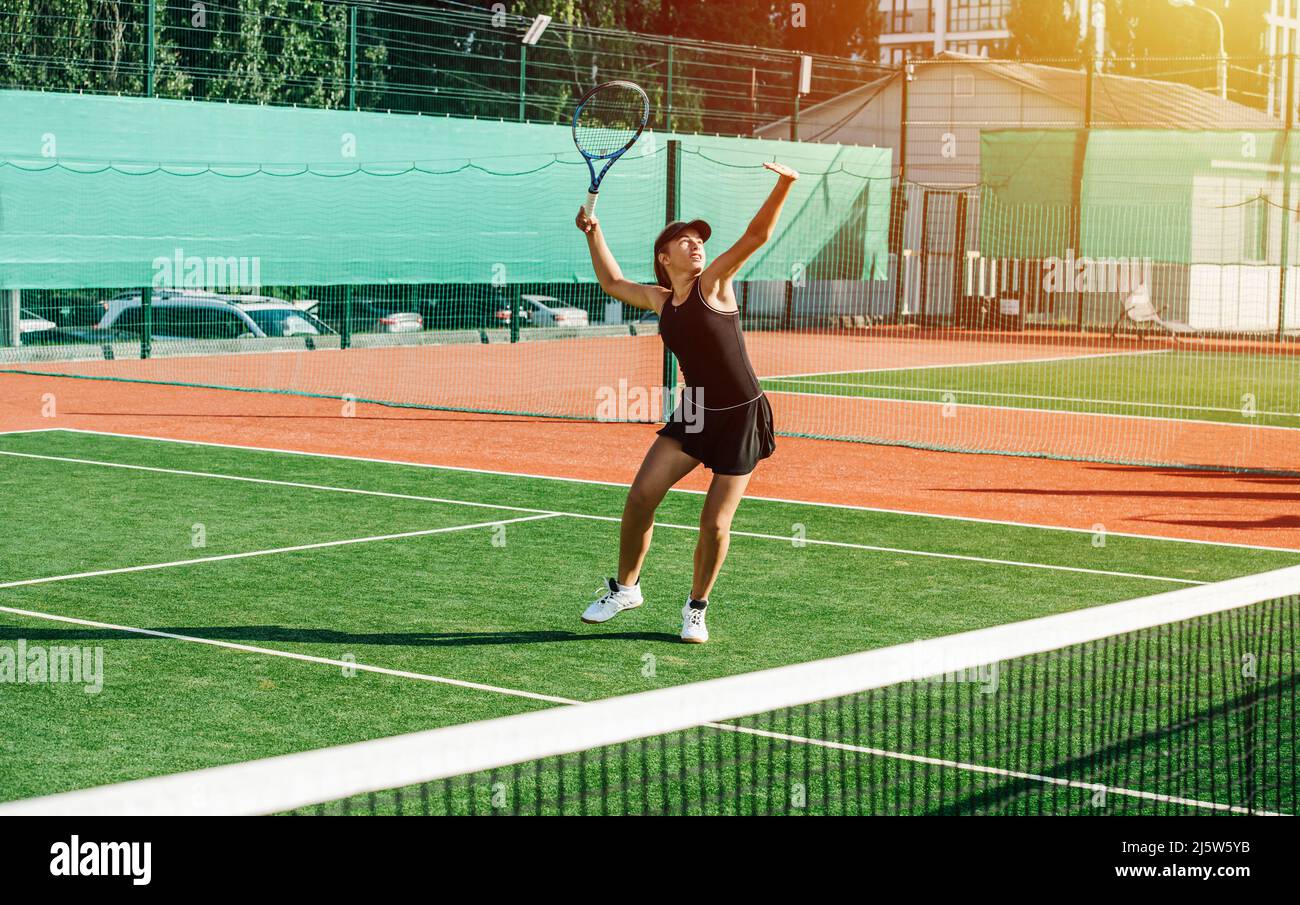 Overhead-Aufnahme eines Mädchens, das auf einem brandneuen Outdoor-Tennisplatz trainiert. Leuchtendes Grün und Braun mit klaren weißen Linien. Ihr Gewicht einzubringen. Sunli Stockfoto