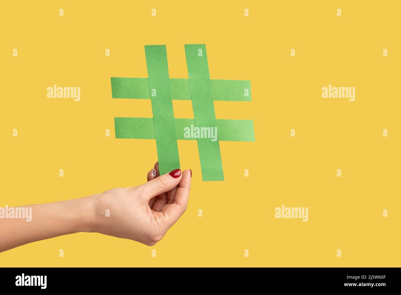 Nahaufnahme einer Frau mit einem großen Hashtag-Symbol aus grünem Papier, Hashzeichen berühmter Medieninhalte, Social Media Marketing und Blog-Werbung. Innenaufnahme des Studios isoliert auf gelbem Hintergrund. Stockfoto