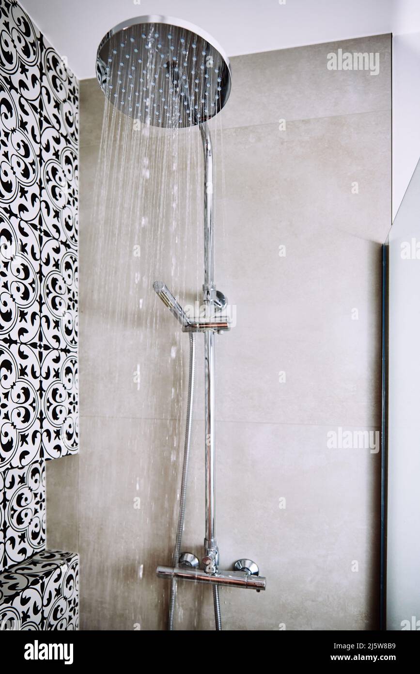 Das Wasser fließt aus dem Duschkopf im Badezimmer Stockfoto