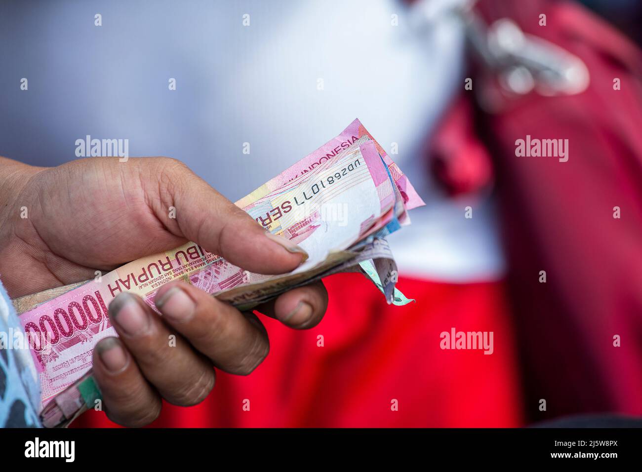 Mann hält indonesisches Papiergeld, Nahaufnahme, Bali, Indonesien. Währung indonesische Rupie Stockfoto
