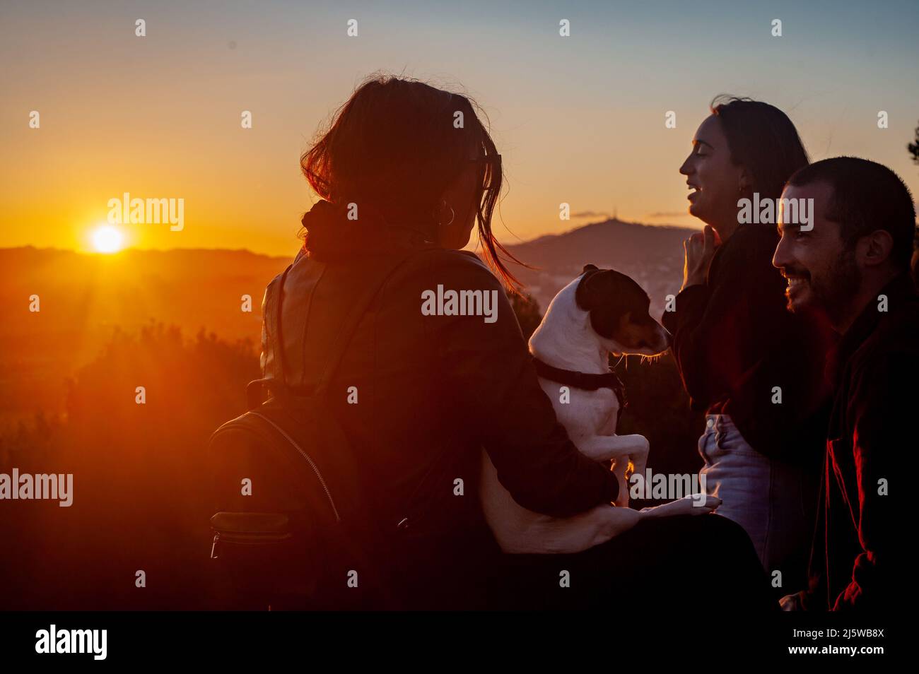 Junge Menschen mit Hund genießen den Sonnenuntergang in Barcelona Stockfoto