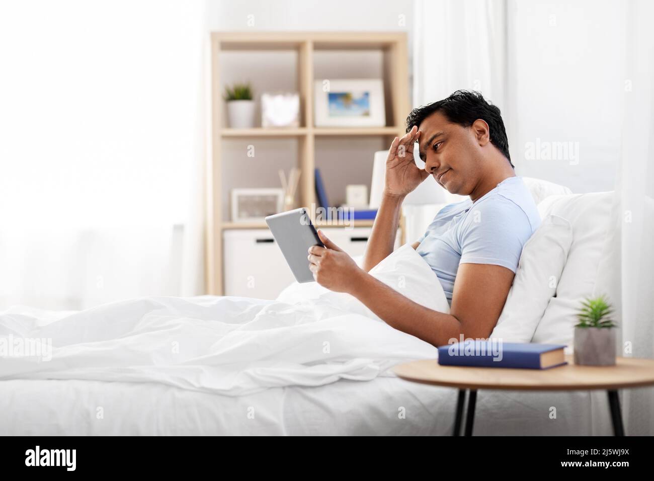 Gestresster indischer Mann mit Tablet-pc im Bett zu Hause Stockfotografie -  Alamy