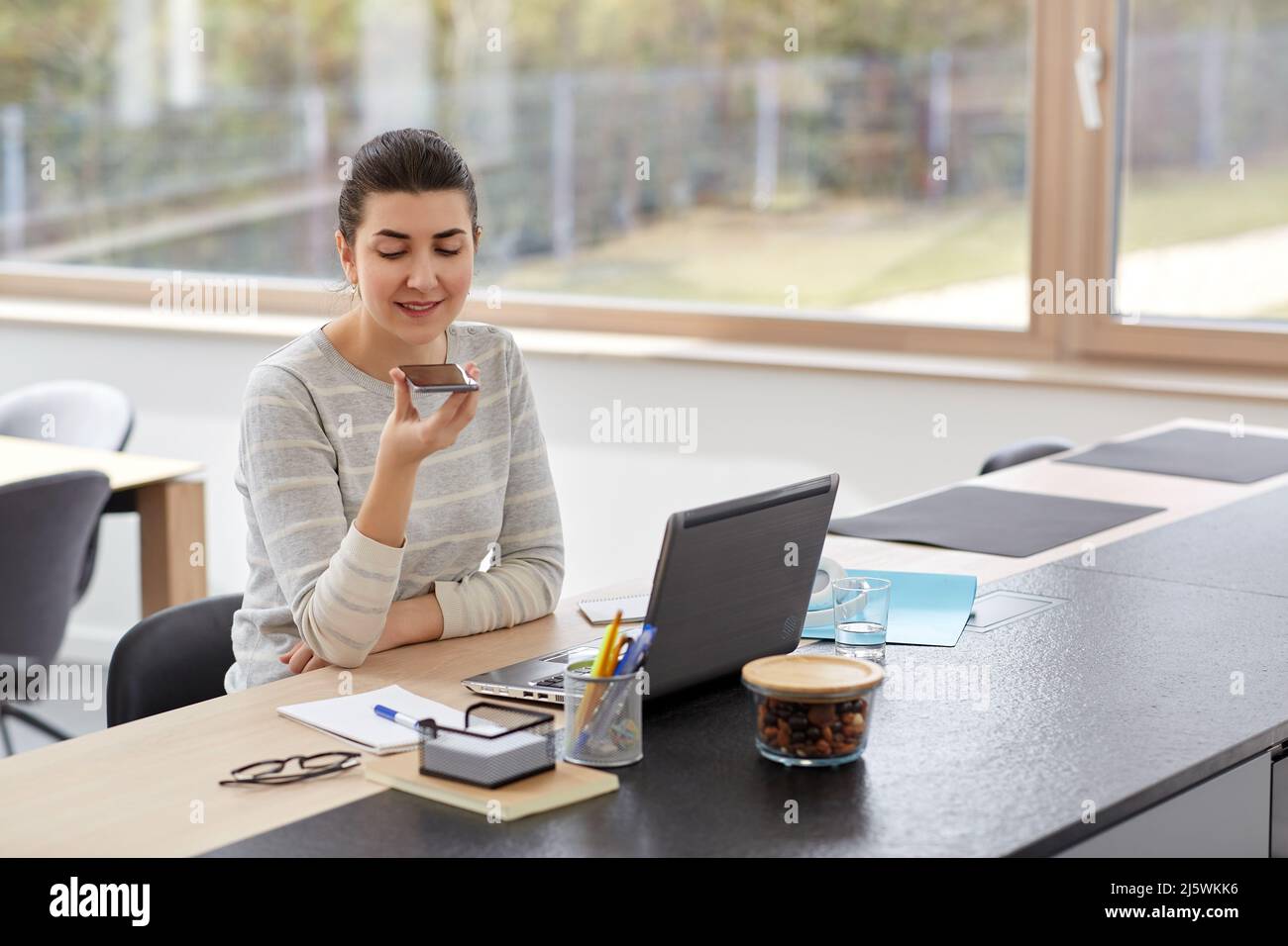 Frau mit Smartphone, die im Büro sprach Stockfoto