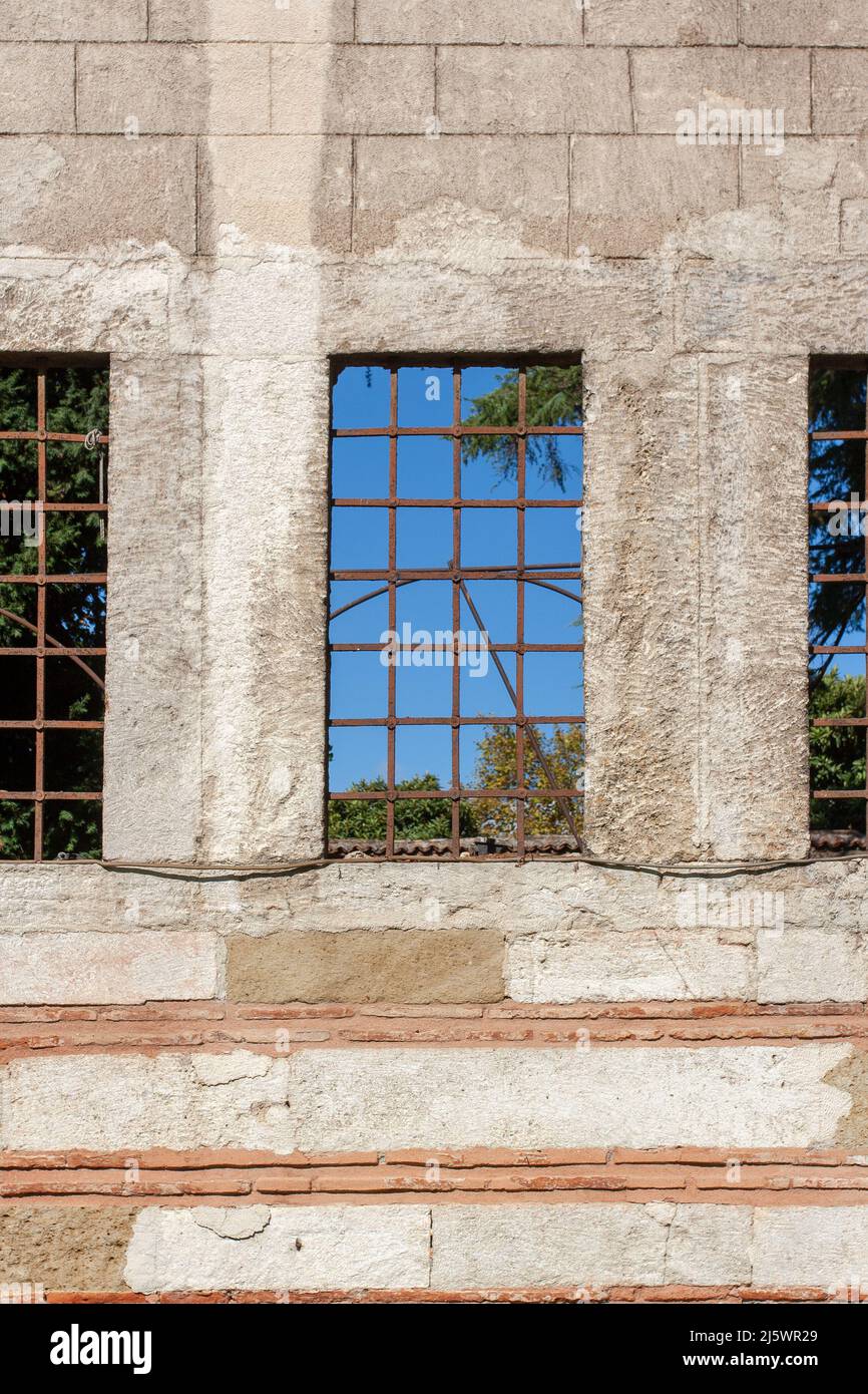 Drei gerillte Fenster in Blockwand mit blauem Himmel auf der anderen Seite. Stockfoto