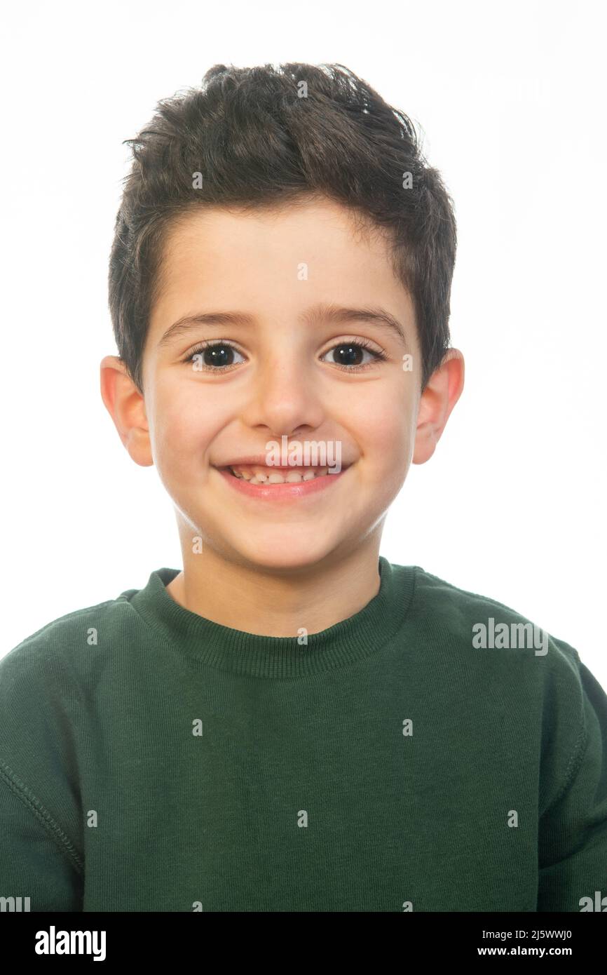 Hübscher 6 Jahre alter Junge, der vor weißem Hintergrund lächelnd auf die Kamera schaut Stockfoto