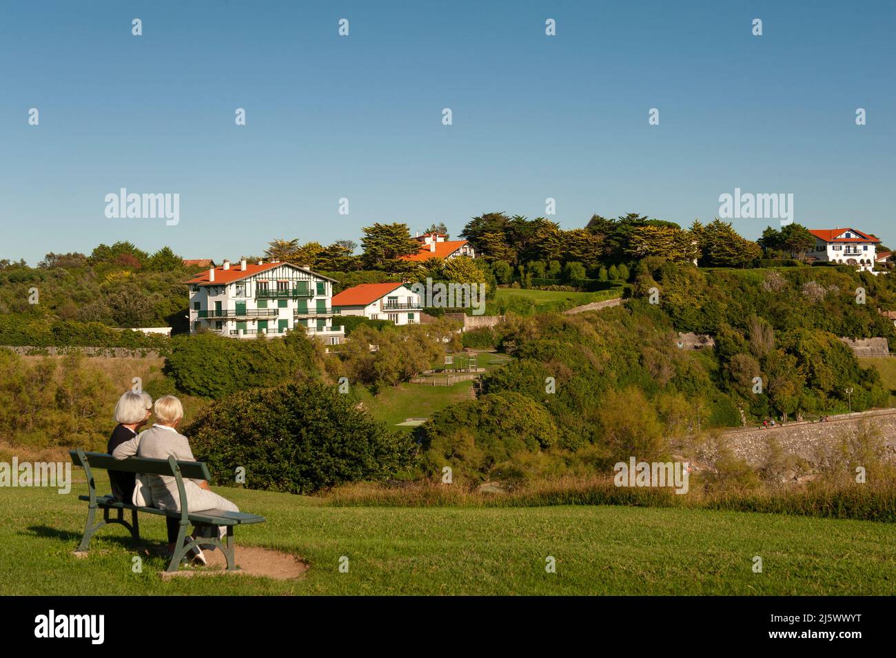 Freunde sitzen auf einer Bank in der Colline Sainte-Barbe von Saint-Jean-de-Luz, Frankreich Stockfoto