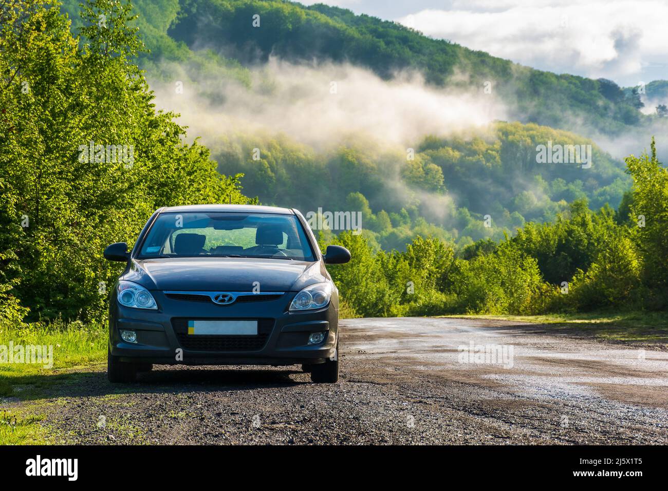 Turya, Ukarine - 17. MAI 2021: Auto auf einer Landstraße am Morgen. Schöne Landschaft im ländlichen Tal an einem sonnigen Morgen. Reisen Landschaft an Stockfoto