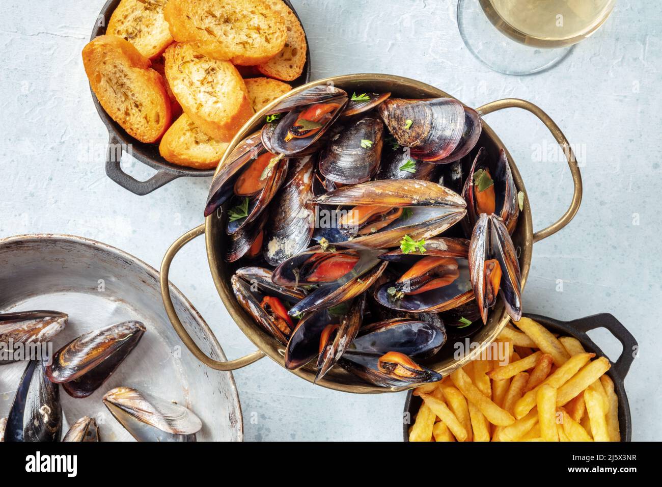 Belgische Muscheln mit Pommes Frites und geröstetem Brot, von oben auf Schiefergrund geschossen Stockfoto