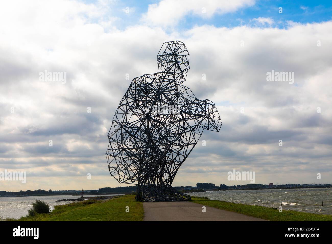 Nahaufnahme des riesigen Kunstwerks aus großem Stahl. Hockender Mann, der am Deich des Markermmersees sitzt. Exposition von Antony Gormley Sept. 2021 Stockfoto