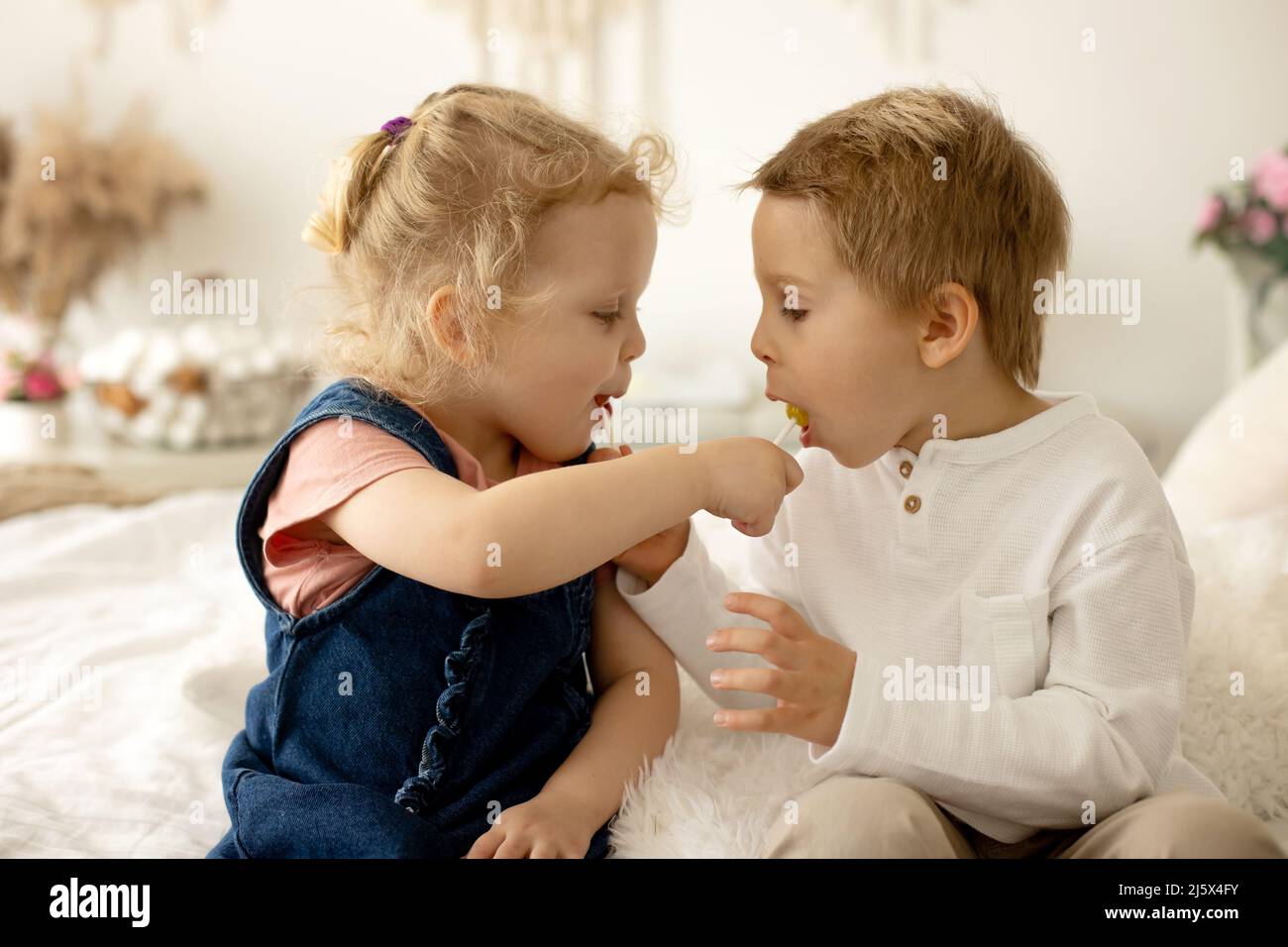 Niedliche Kleinkinder, Junge und Mädchen, essen Lolly Pop zu Hause, genießen Süßigkeiten Stockfoto