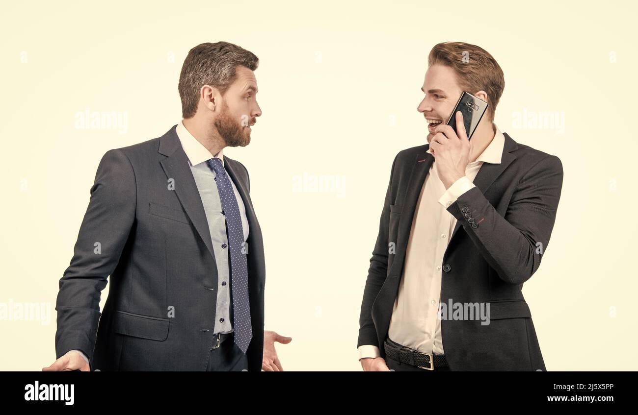 Wütender Chef streitet mit lächelndem Mitarbeiter, der am Telefon spricht, isoliert auf Weiß, Konflikt Stockfoto