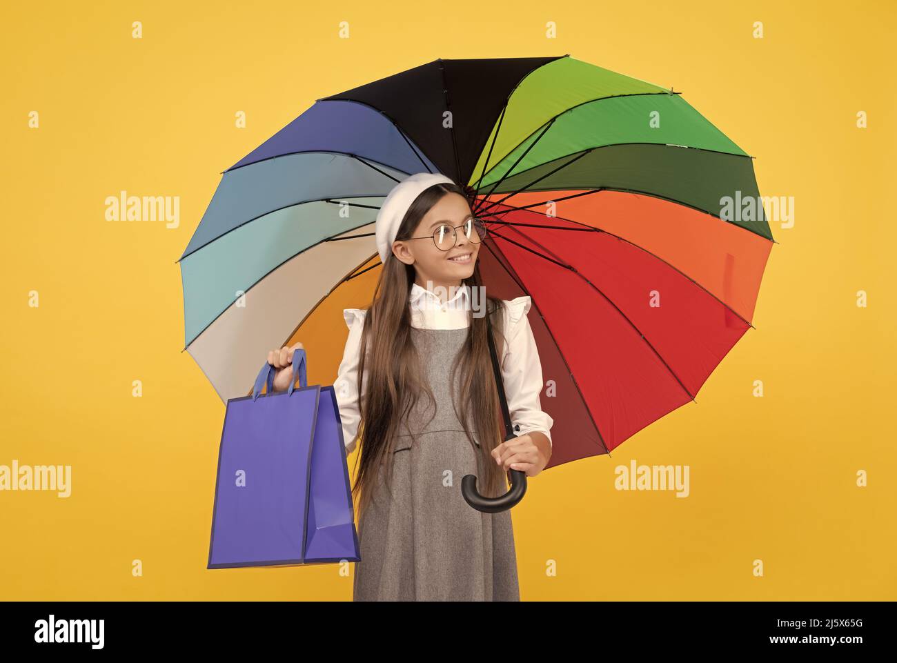 Saisonaler Verkauf. Jugendlich Kind unter bunten Sonnenschirm. Kind Baskenmütze mit Regenbogenschirm. Herbstsaison. Stockfoto