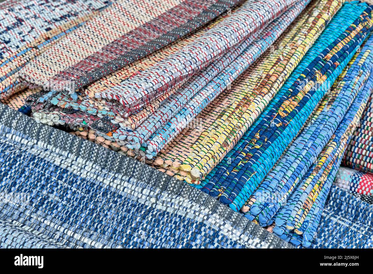 Hausgemachte bunte gewebte Teppiche aus Stoffbändern gestapelt. Nahaufnahme. Stockfoto