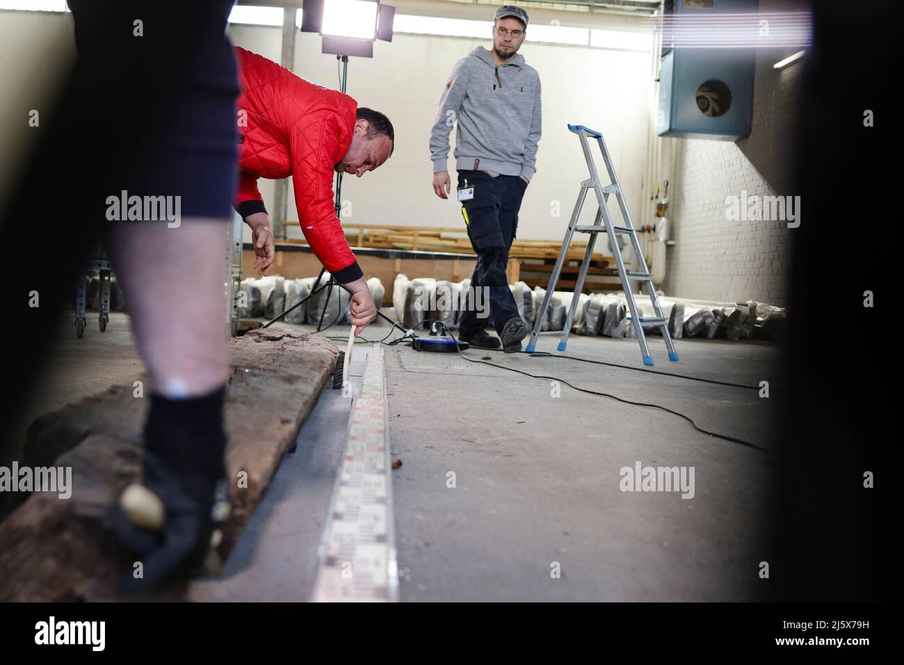 26. April 2022, Schleswig-Holstein, Jübeck: Janosch Willers (r) vom Archäologiemuseum Schloss Gottorf in Schleswig blickt auf eine rund 1600 Jahre alte Holzsäule. Der Fund gehört zu den Grabkammern, die 2005 in Poprad-Matejovce in der Slowakei entdeckt wurden. Das Landesmuseum Schloss Gottorf in Schleswig beteiligte sich gemeinsam mit Wissenschaftlern aus sieben europäischen Ländern an der Erhaltung des Holzes. Der Grabbeistand gehört zum späten 370s n. Chr. Die Grabfunde stammen aus dem späten Jahr 370s n. Chr., d.h. aus dem Übergang zwischen der römischen Kaiserzeit und der frühen Migration per Stockfoto
